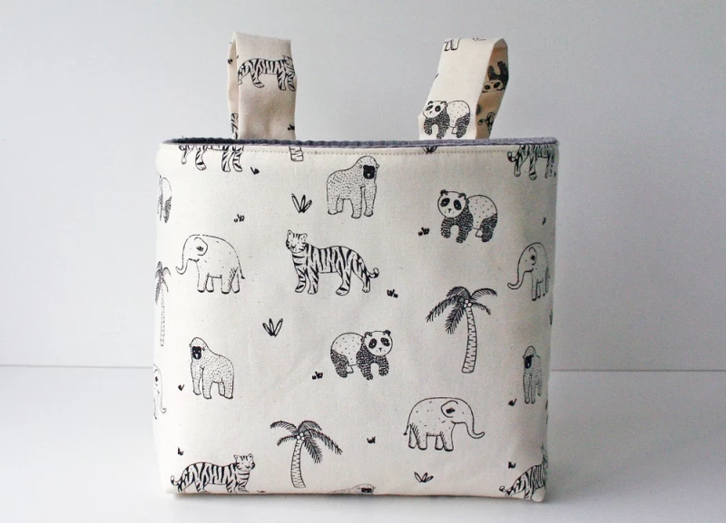 beige farbene Hängetasche mit schwarzen Outline Tieren